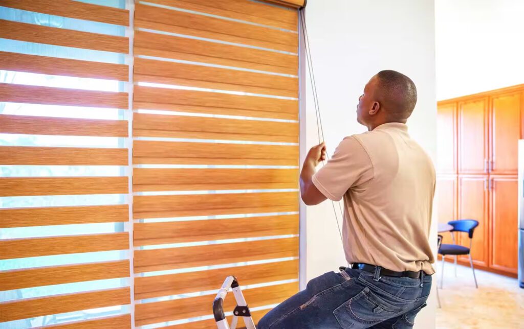 A man installing window blinds in home at at High Point, NC.